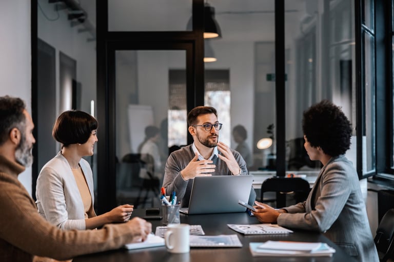 Senior mentor guiding team in strategic business discussion at boardroom