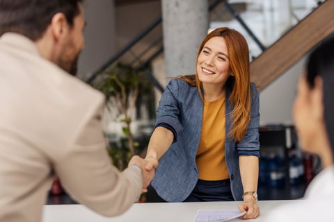 Portrait of friendly smiling female boss shaking hands with businessman on a briefing at corporate office