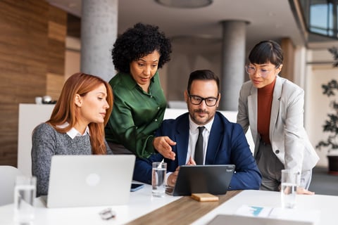 Professionals collaborate in a modern office environment with laptops and tablets, fostering teamwork and productivity