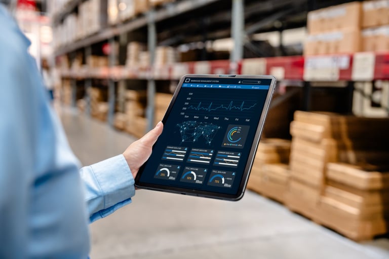 Businessman using digital tablet with warehouse management system dashboard on screen, monitoring inventory, delivery, and supply chain analytics